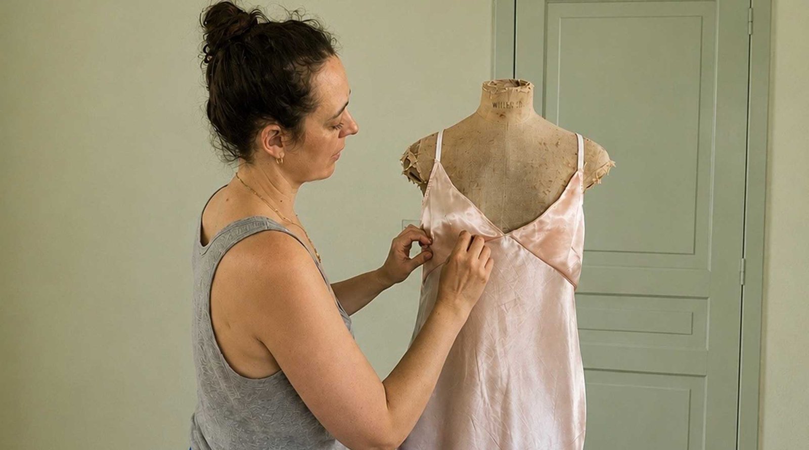 Designer fitting a bespoke lingerie prototype on a dress form in the atelier.